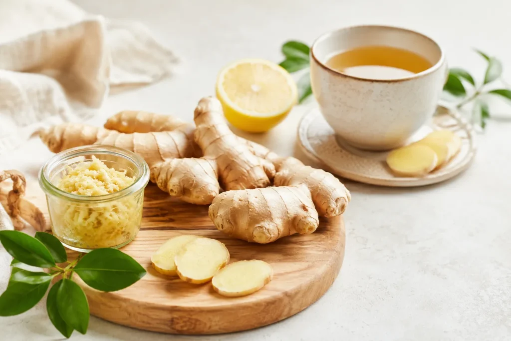 Gengibre fresco, gengibre ralado, limão e chá de gengibre em composição clean de cozinha natural.