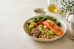 fotografia editorial clean de uma mesa clara com prato colorido de comida de verdade: vegetais, leguminosas, azeite, sementes, ovos ou peixe, com elementos naturais ao redor.